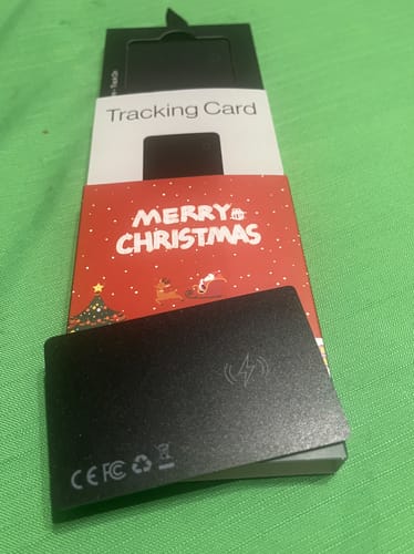 Customer's black SPOTMINDERS Tracking Card resting on its festive packaging with a Merry Christmas sleeve.