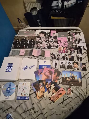 Reviewer's three STRAY KIDS DO IT SKZ IT TAPE albums and all their contents, like photocards and booklets, spread across a bed.