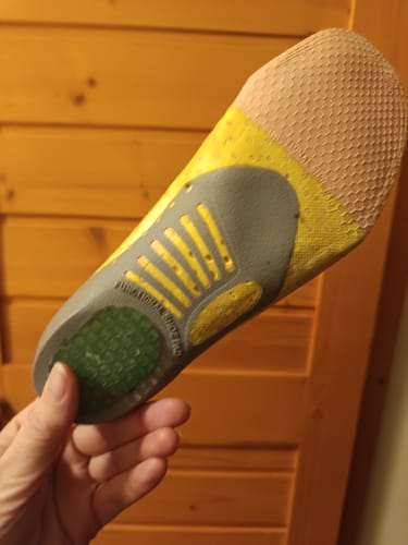 Vásárló mutatja a sárga és szürke Ortopéd Pro Talpbetétet a kezében.