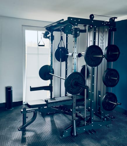 Ein Kunde zeigt sein aufgebautes SEK Multipresse Set in einem privaten Fitnessraum mit Hantelbank.