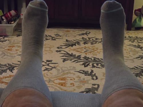 Reviewer relaxing with their feet up while wearing the grey, comfortable Premium Bamboo Compression Socks.