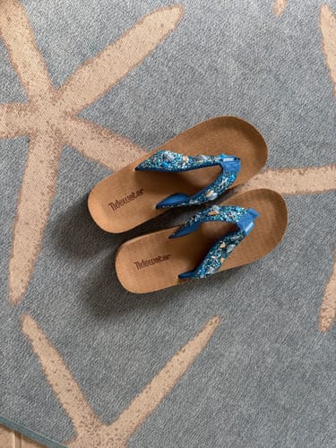 Customer's 'A Walk on the Beach' flip flops with sparkly blue straps, shown on a starfish patterned rug.