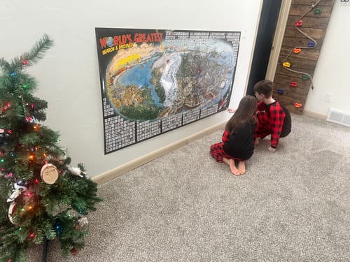 Customer's two children in pajamas looking closely at the World's Greatest Search & Discover poster on a wall.