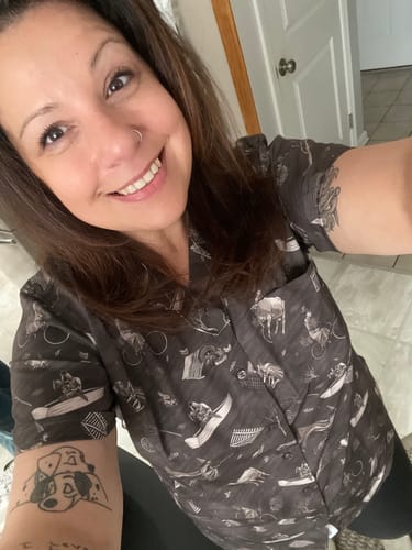Reviewer smiling while wearing the dark, patterned Wizard of Oz "Wicked Winds" short sleeve shirt.