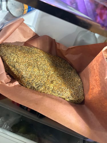 Customer's USDA Prime Brisket, heavily seasoned and resting on brown butcher paper in a refrigerator.