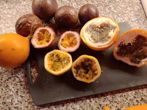 Ein Kunde zeigt verschiedene ganze und aufgeschnittene Passionsfrüchte aus der 'Passiflora Lovers' Maracuja-Mix Box.