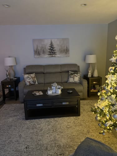 Customer's Snowy Christmas Tree wall art hanging above a sofa in a living room decorated for Christmas.