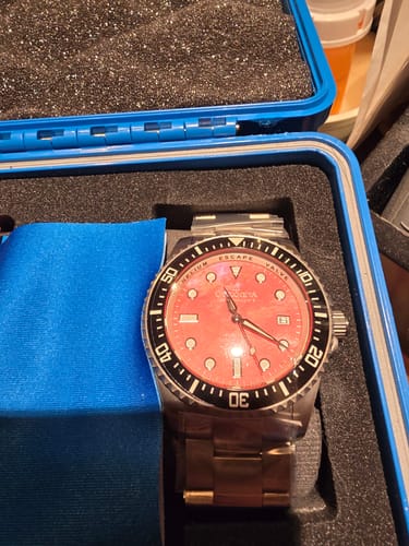 Reviewer's Oceaneva Deep Marine Explorer II watch angled in its case, showing the red mother of pearl dial shimmering.