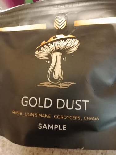Close-up of a reviewer's black sample pouch for Gold Dust mushroom blend.