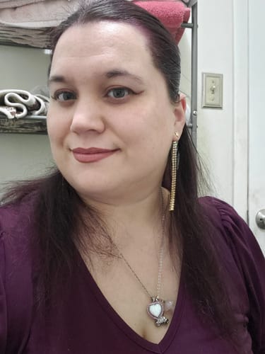 Reviewer showing their dark hair with a purple tint after using the Instant Dye Shampoo.