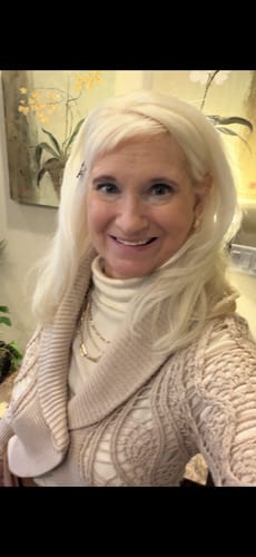 Customer smiling while wearing the Peyton Turtleneck in buttercream, layered under a cozy beige cardigan.