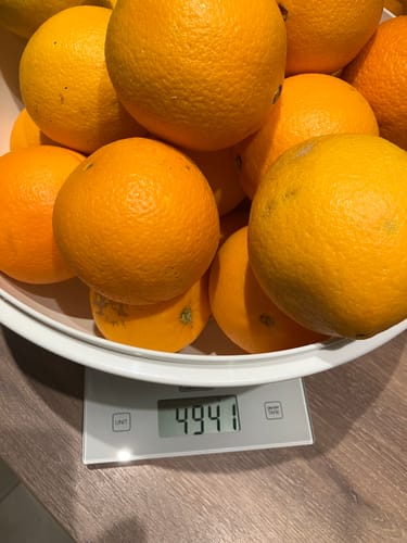 Ein Kunde wiegt seine Orangen Navelina Bio in einer Schüssel auf einer Küchenwaage, die 4941g anzeigt.