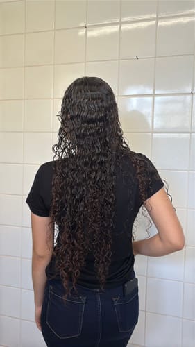 Cliente de costas mostrando seu cabelo comprido e cacheado para a avaliação do produto Happy Hair.
