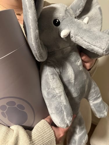 Klant houdt de zachte, grijze Olifant verzwaringsknuffel vast, met de verpakking ernaast.