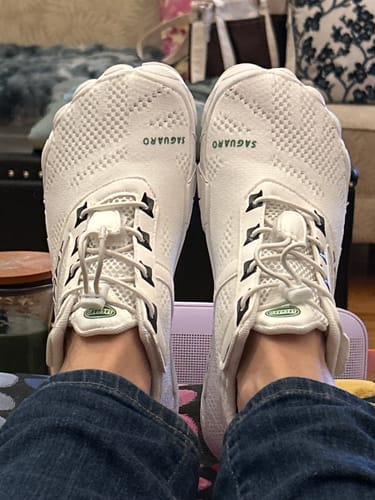 Reviewer relaxing indoors, wearing a pair of white Free I - Barefoot Shoes with their feet up.