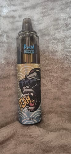 Ein Kunde zeigt den bunten RANDM TORNADO 9000 Vape in der Geschmacksrichtung Mixed Berries auf einer weichen Oberfläche.