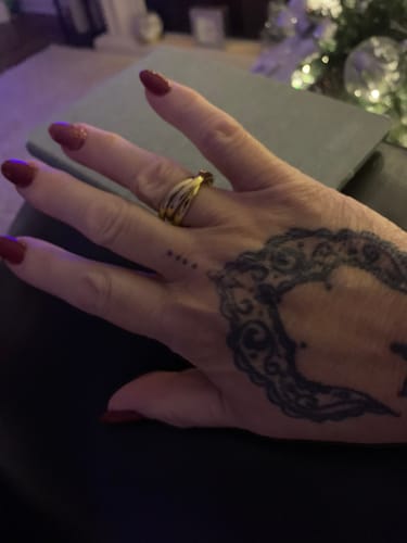 Close-up of a reviewer's hand with a tattoo wearing the gold Havana Curb Ring Stack.