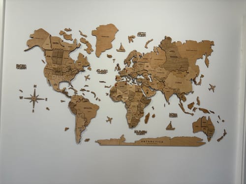 Customer's assembled 3D Wooden World Map mounted on a white wall, showing detailed wooden continents.