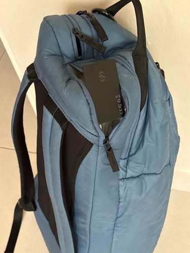 Customer's black SPOTMINDERS Tracking Card shown in the side pocket of a blue backpack.