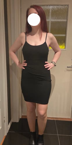 Reviewer standing indoors wearing the black, form-fitting Slip Mini Shapewear Dress.