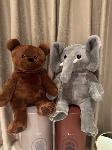Recensent toont de zachte Beer en Olifant verzwaringsknuffels die naast elkaar op hun verpakking zitten.
