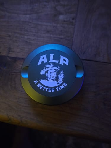 Customer's round, green ALP can with an 'A Better Time' logo, shown on a dark wooden table.