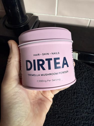 Customer holding a pink tin of DIRTEA Tremella Mushroom Powder in their hand.