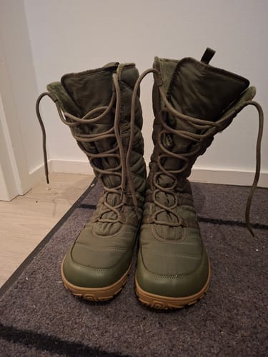 Asiakkaan vihreät Vaistoa Hanki 2 -paljasjalkatalvisaappaat seisomassa matolla sisätiloissa.