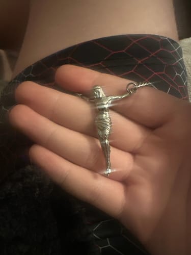 Customer holding the detailed silver JESUS CHAIN pendant in their open palm.