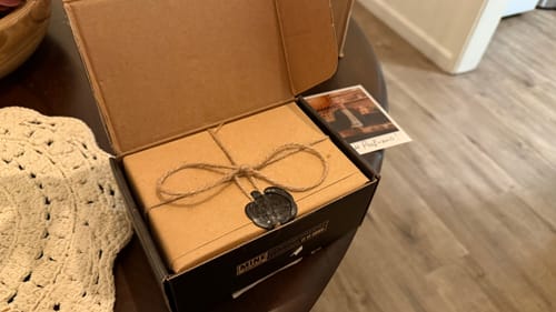 Recensore mostra la confezione regalo del profumo Vesevo, legata con spago e un sigillo di cera nera.