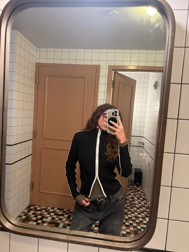 Reviewer wearing the black contrast full-zip cardigan, partially unzipped from the bottom, in a mirror selfie.