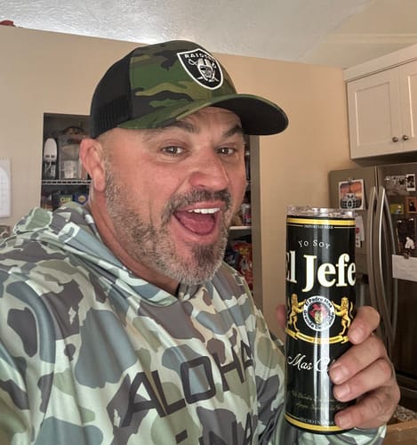 A happy customer holds up the black 'El Jefe' stainless steel tumbler in their kitchen.