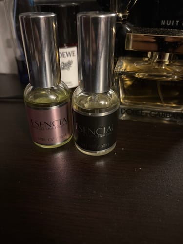 Reseñador muestra dos frascos del perfume H041 sobre una mesa oscura junto a otras fragancias.