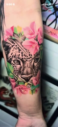 Customer's forearm showing a detailed leopard and flower tattoo achieved using Painless Tattoo numbing cream.