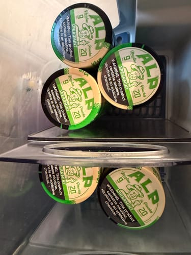 Customer's several tins of Spearmint Nicotine Pouches stacked neatly on a refrigerator shelf.