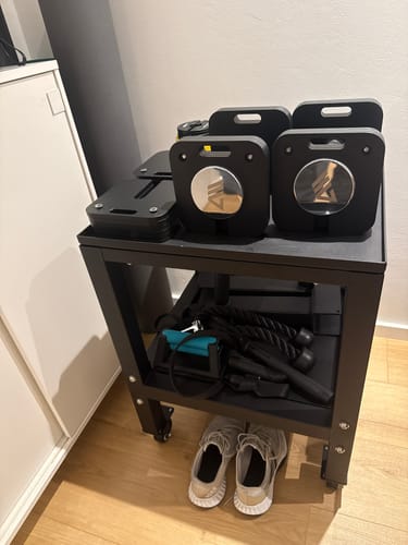 Kunde zeigt die hochwertige QUAD Hantelablage mit Hanteln oben und weiterem Zubehör auf der unteren Ablage.