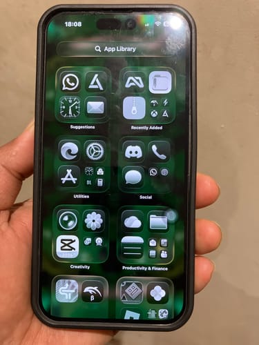 Reviewer holds a refurbished iPhone 14 Pro Max in a black case, with the screen turned on.