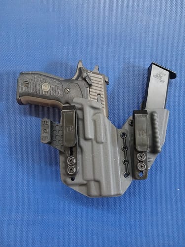 Customer's grey AXIS ELITE holster holding a full-size handgun and a spare magazine against a blue background.