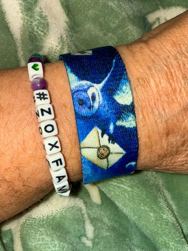 Customer wearing a blue wristband from the Magical Mystery 3-Pack with a detailed owl and letter design.