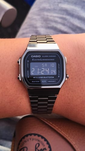 Cliente mostrando su reloj Casio Vintage A168WGG-1BDF en la muñeca. El reloj tiene una correa metálica oscura y esfera digital.