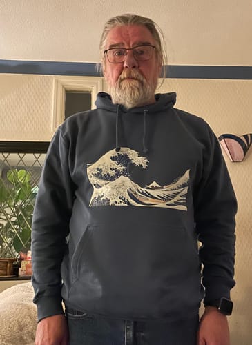 Reviewer wearing a dark College hoodie with a large wave graphic printed on the front.