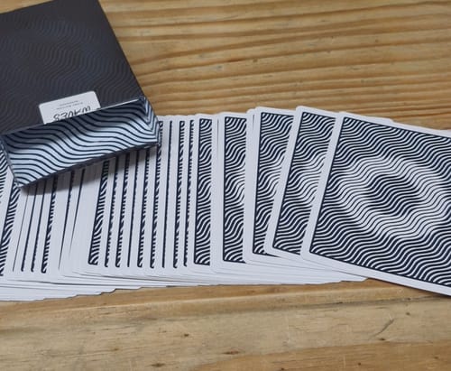 Customer's deck from a Mystery Deck purchase, fanned out on a wooden table to show the wavy, black-and-white back design.
