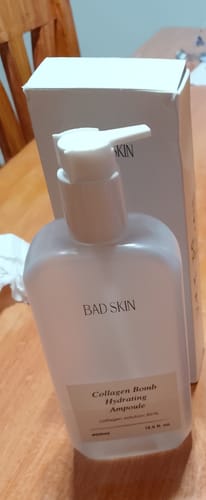 Customer's Bad Skin Korean Collagen Bomb Hydrating Ampoule pump bottle sitting on a wooden table with its white box.