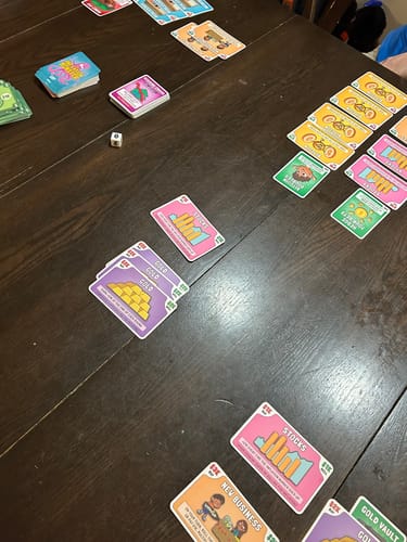 Reviewer's Tuttle Twins Inflation Monster Card Game in progress, with colorful cards spread out on a dark wood table.