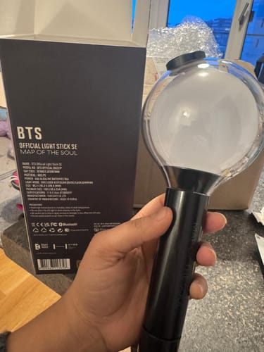 Customer holding the BTS Official Light Stick Map of the Soul Special Edition, with the product box visible in the background.