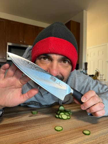 Reviewer holds the shiny 8" High Carbon Chef Knife, showing its intricate Damascus-style pattern.