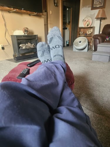 Reviewer wearing the grey Men's Alpaca Socks with their feet propped up indoors.