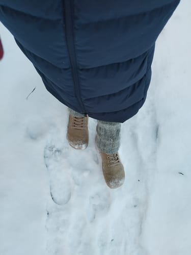 Arvostelijan ruskeat Vaistoa Tunto 2 -tennarit ja villasukat lumisessa maastossa ylhäältä kuvattuna.