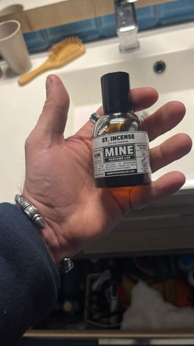 Cliente che tiene in mano la boccetta del profumo ST INCENSE in bagno.