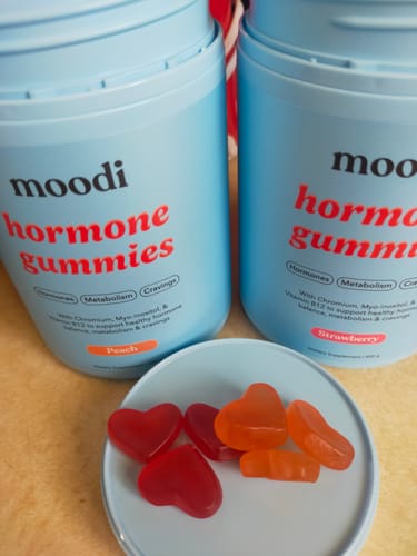 Customer's Hormone Gummies Bundle, showing the peach and strawberry containers with red and orange heart-shaped gummies in the foreground.